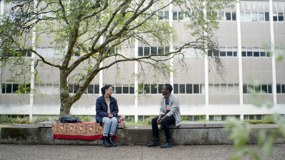 Photo of two people sitting on a bench and facing each other and talking